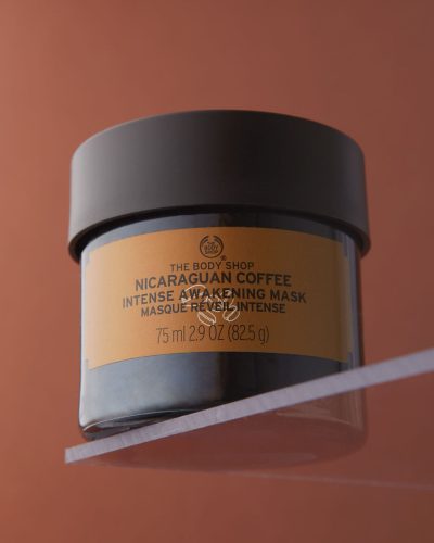 A professional hero-shot picture of a BodyShop coffee face mask on a matching brown background