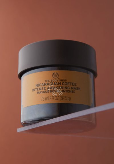 A professional hero-shot picture of a BodyShop coffee face mask on a matching brown background